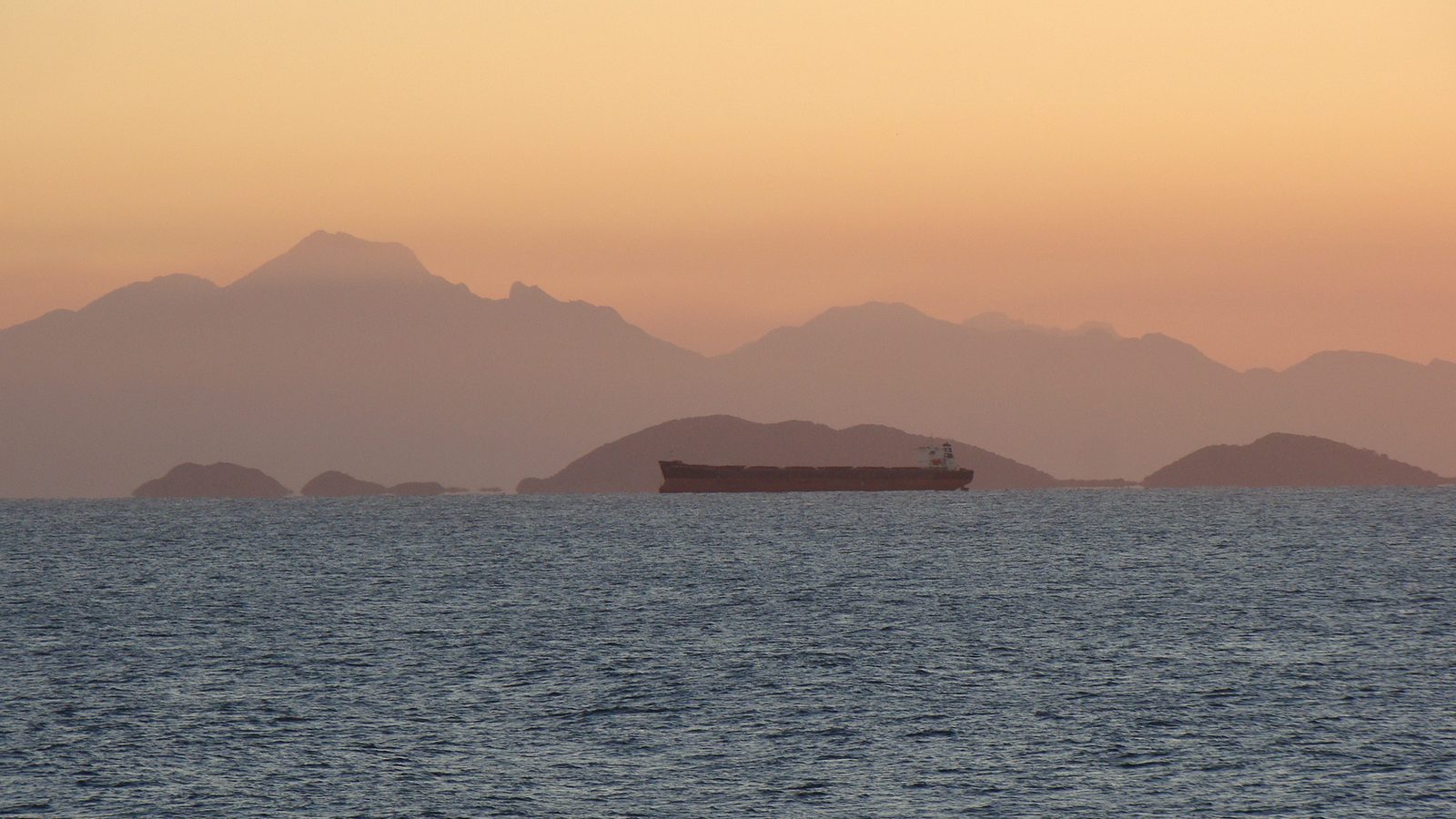 Navio fundeado ao entardecer na baía de Paranaguá com a serra ao fundo